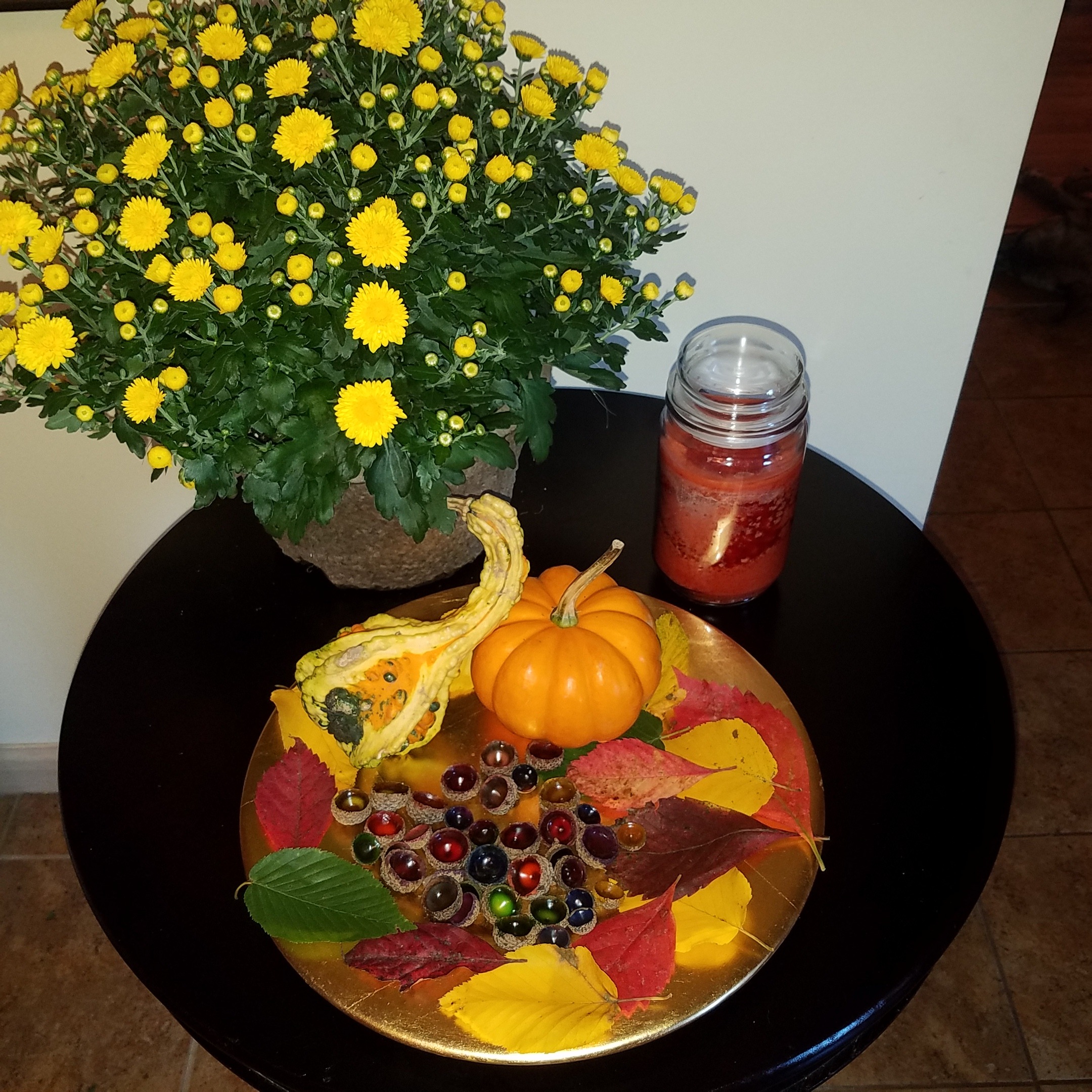 Colorful Fall centerpiece containing acorn gems, small pumpkin, and yellow mums